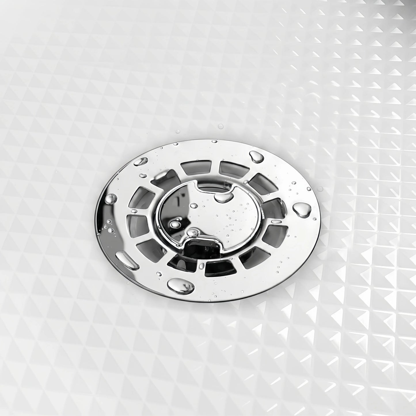 Close-up of Veloaura 2-inch round mirror-polished 304 stainless steel no caulk shower pan drain with water droplets on a white textured shower pan.