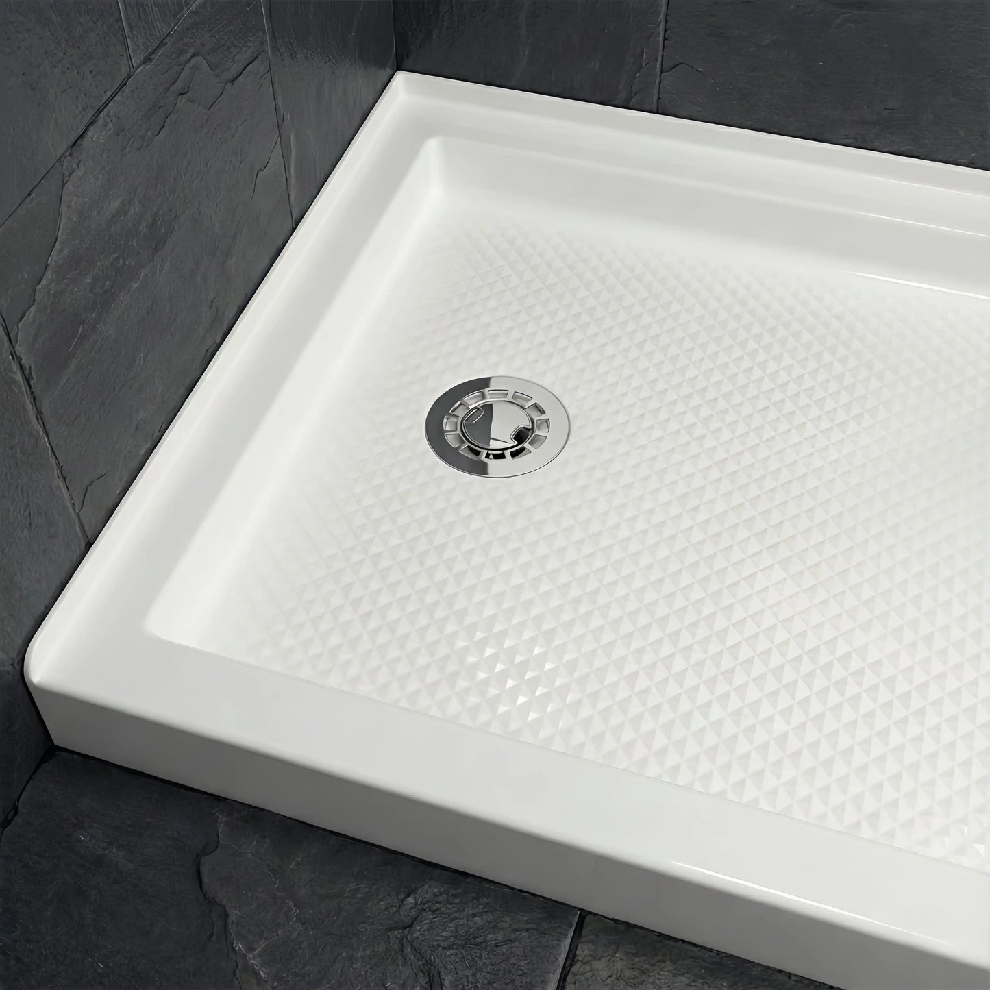 Full view of a Veloaura 2-inch no caulk shower pan drain installed in the center of a modern white shower base with dark slate walls.