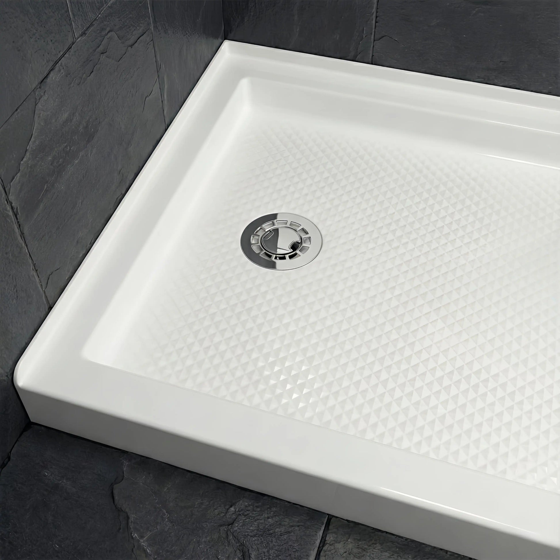 Full view of a Veloaura 2-inch no caulk shower pan drain installed in the center of a modern white shower base with dark slate walls.