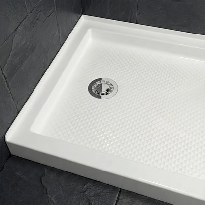 Full view of a Veloaura 2-inch no caulk shower pan drain installed in the center of a modern white shower base with dark slate walls.