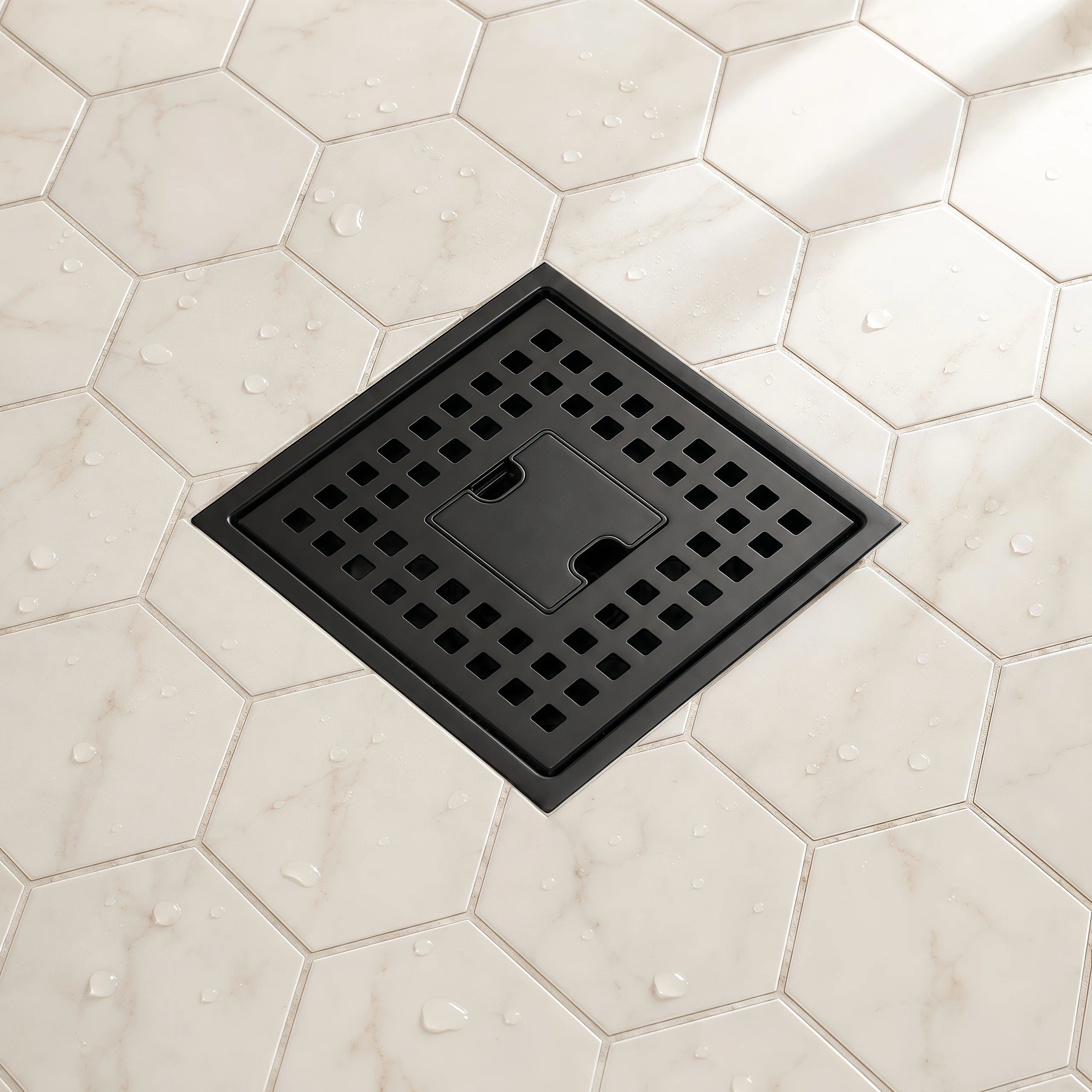 Veloaura 6 inch matte black square shower drain installed on a white hexagon tile shower floor