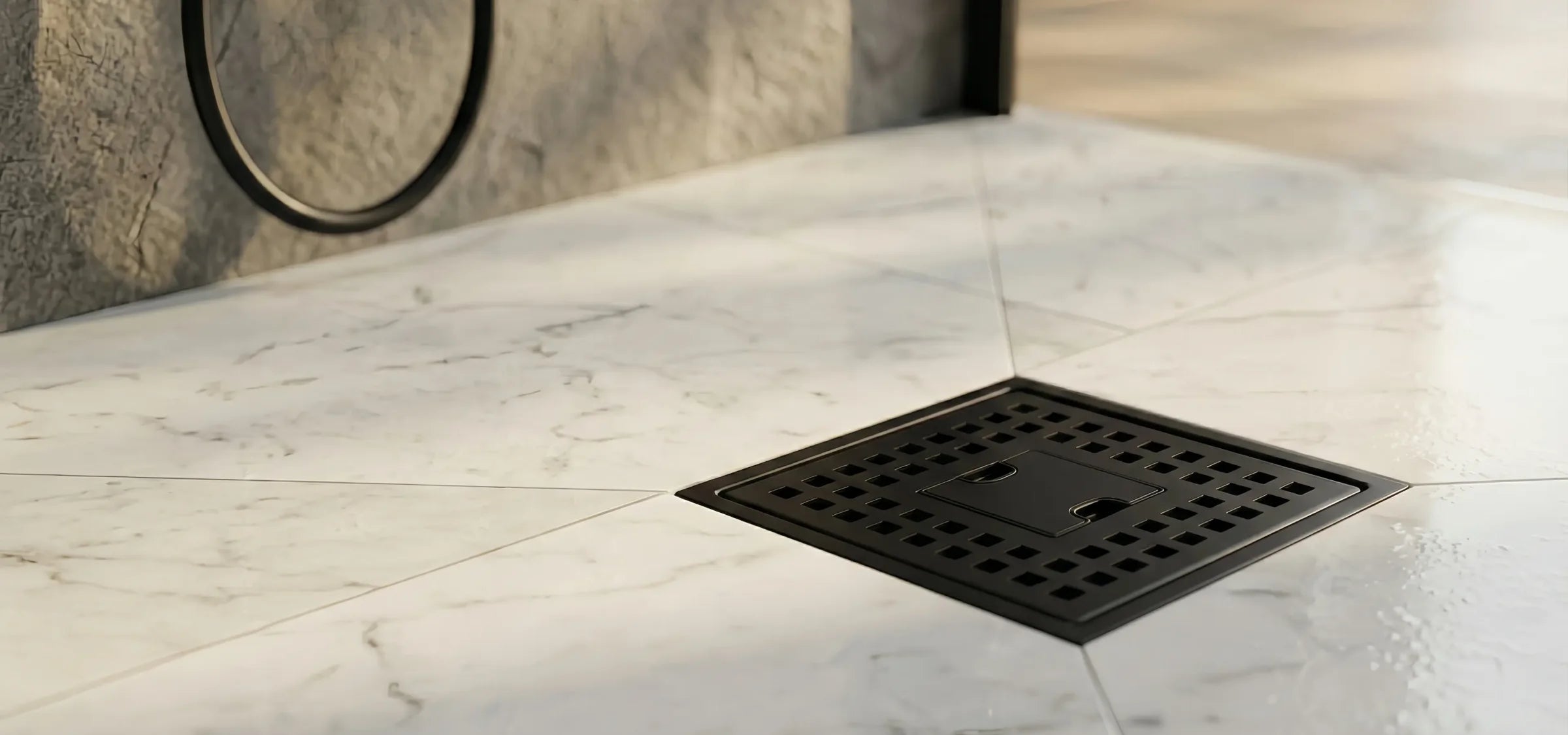 Veloaura matte black square shower drain installed on a marble tile shower floor